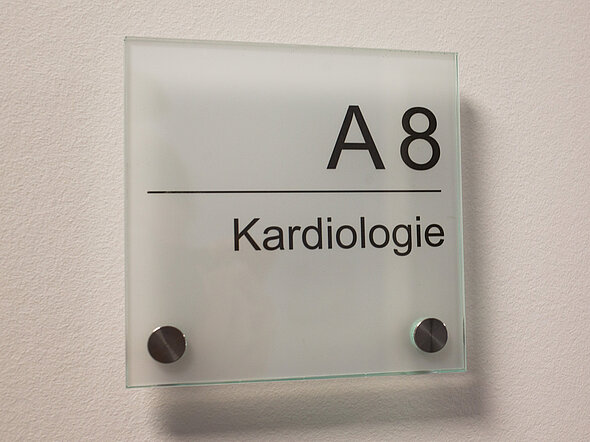 Das Bild zeigt ein Schild, auf dem A8, Kardiologie steht. So beschriften wir unsere Behandlungsräume.