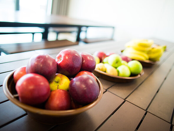 Hier stehen zwei Schalen mit Obst auf einem Tisch. Obst gibt es immer für Mitarbeitenden gratis. 
