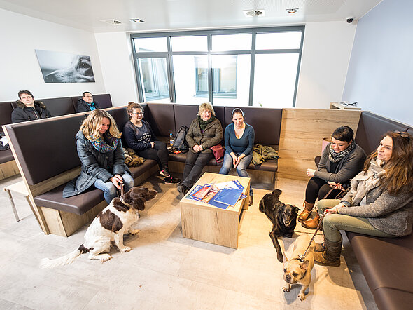 Hier sieht man eines unserer Hundewartezimmer. Mehrere Besiter:innen warten zusammen mit ihren Tieren auf den Termin.