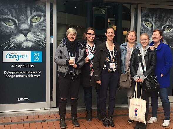 Hier stehen fünf Tiermedizinische Fachangestellte vor einer Saaltür bei einem interantionalen Kongress in Birmingham. 