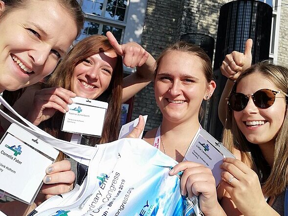 Hier sieht man vier Tiermedizinische Fachangestellte, die ihre Teilnehmerausweise für eine internationale Tagung in Tallin in die Kamera halten. 