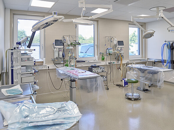 Auf diesem Bild sieht man einen unserer OP-Räume. Es sind zwei OP-Tische zu sehen, die OP-Lampen und die Anästhesietürme. Außerdem gibt es einen Tisch mit Verbrauchsmaterial darauf.